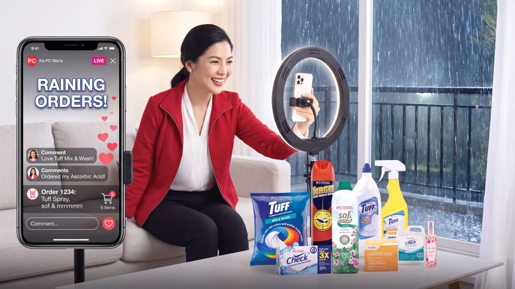 A woman smiling and hosting a live shopping broadcast on her phone, while being surrounded by Personal Collection household products.