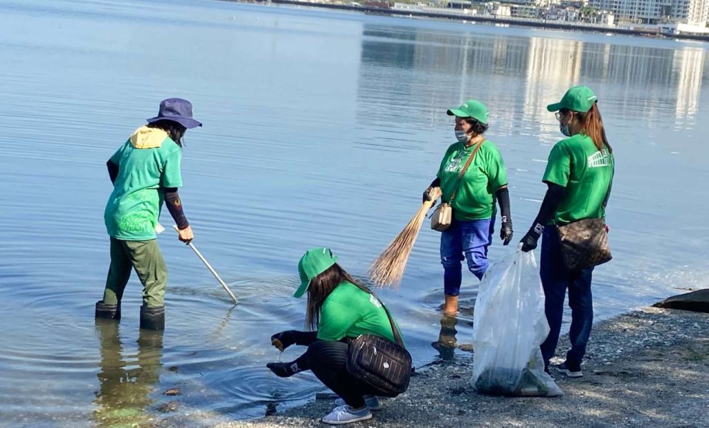 volunteers picking up trash on a lakeside